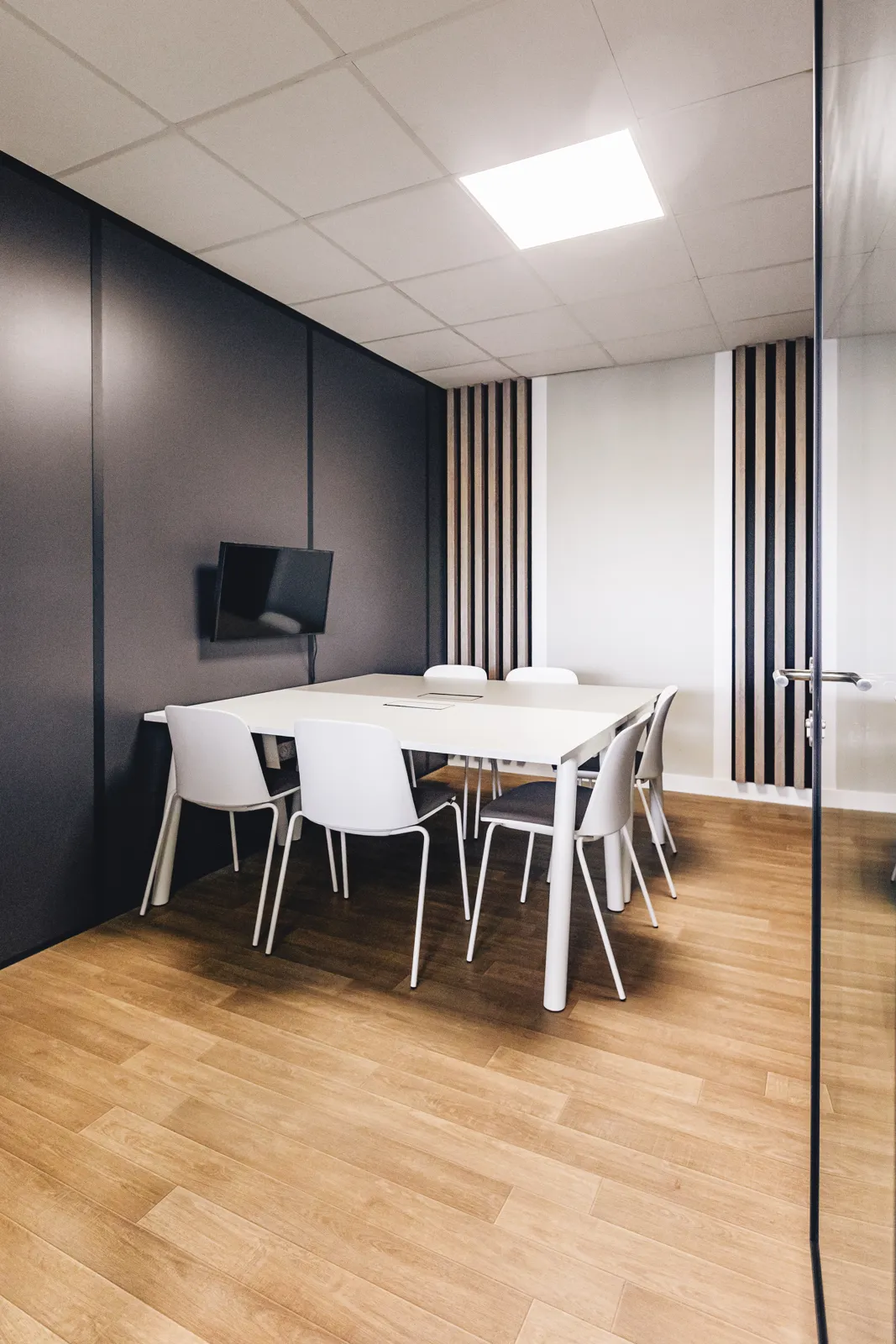 Petite salle, table blanche et écran mural