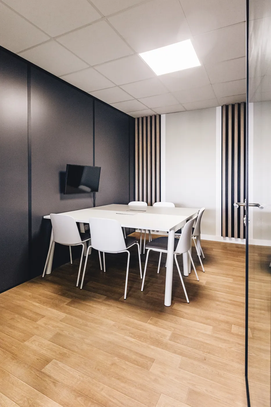 Petite salle de réunion, table blanche et écran mural
